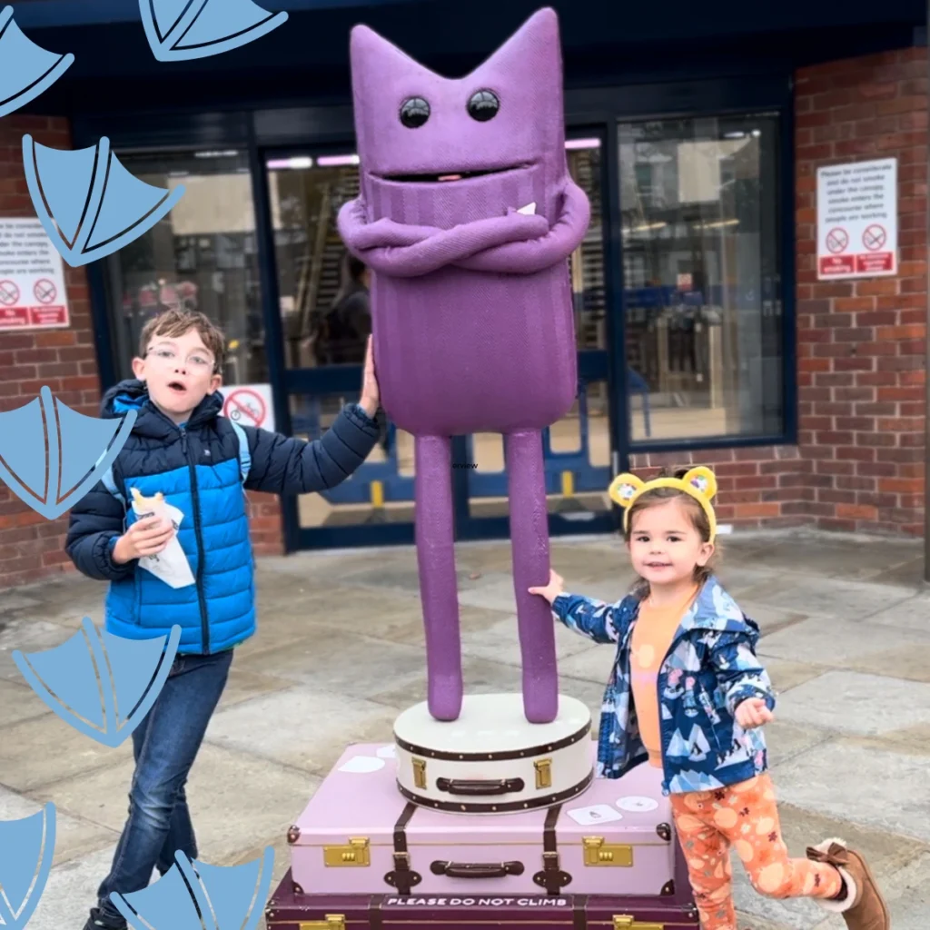 kids at derby train station next to the purple statue