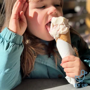 little girl eating Derbyshire ice cream in a waffle cone in a green dress.