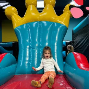 little girl sitting on inflatable chair with crown on top at derby soft plays