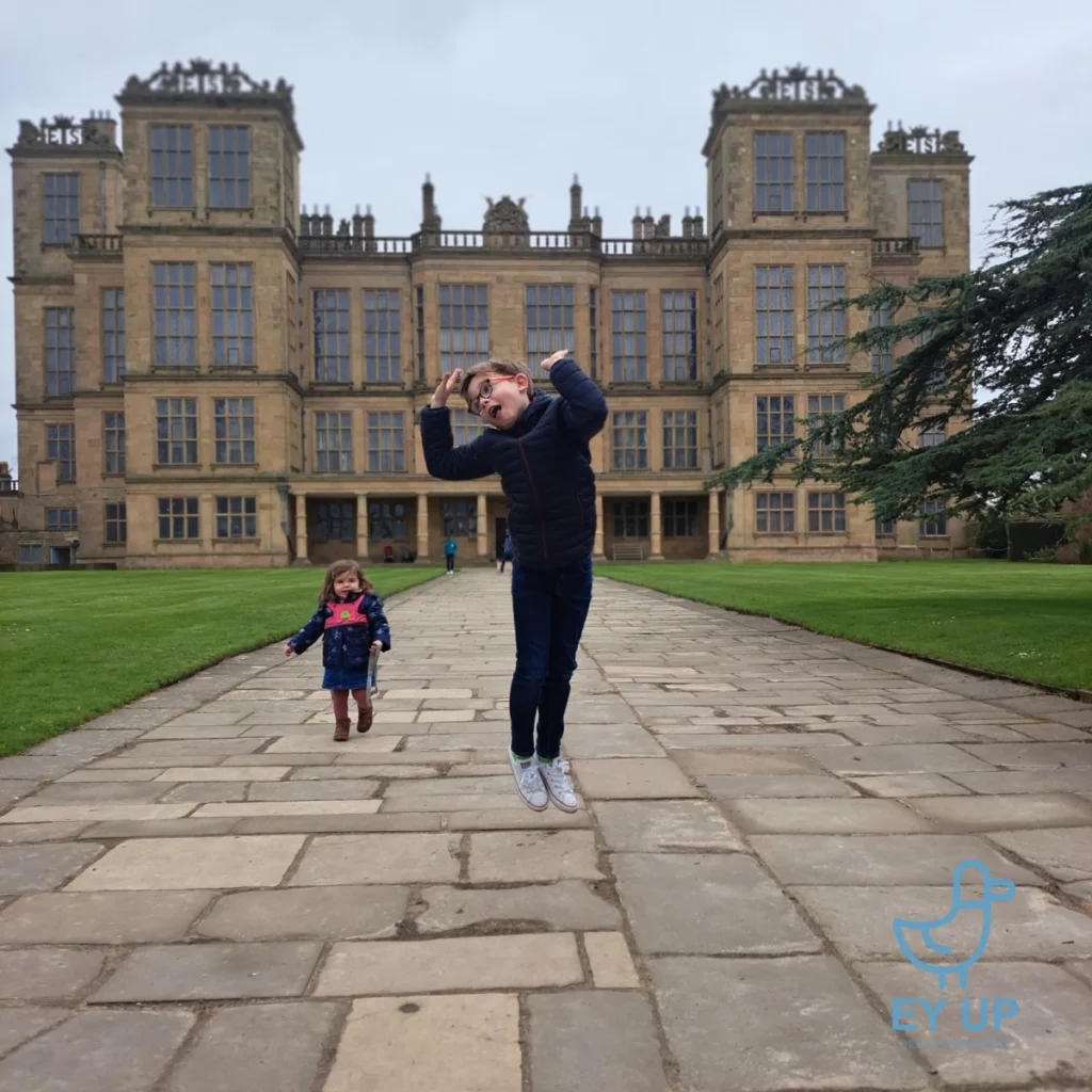 Twi children jumping in front of Hardwick Hall Derbyshire