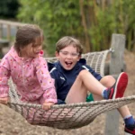 two children laughing in a playground in Derbyshire on a play net