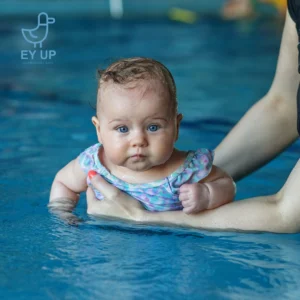 baby in the baby class in the swimming pool with mum holding her